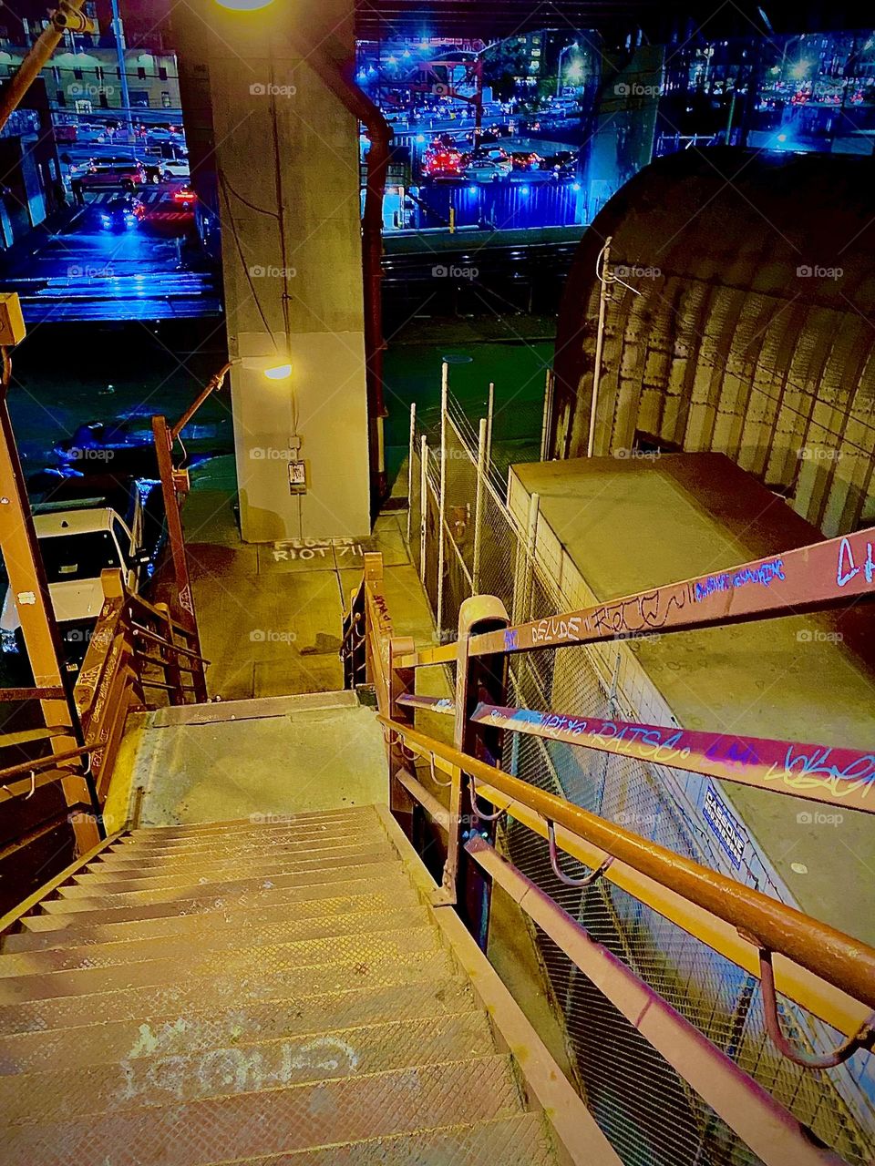 Here is the staircase descending from the pedestrian lane of the bridge down the red metal staircase to street level respectively the parking lot beneath the “Pulaski Bridge” in LIC, Queens, NY. 2022. Hypnotic Productions