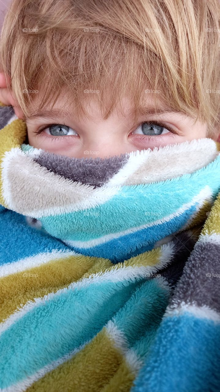 boy covers his face with a blunket