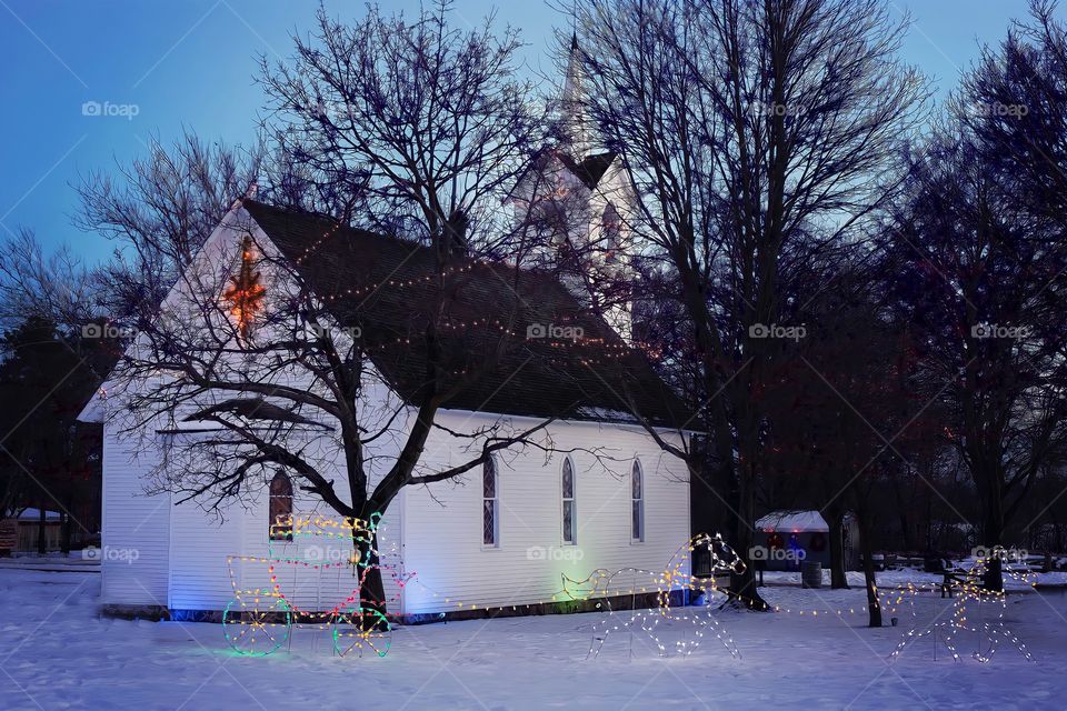 Church With Christmas Lights In Snow
Landscape view of countryside church with trees and Xmas lights in snow.