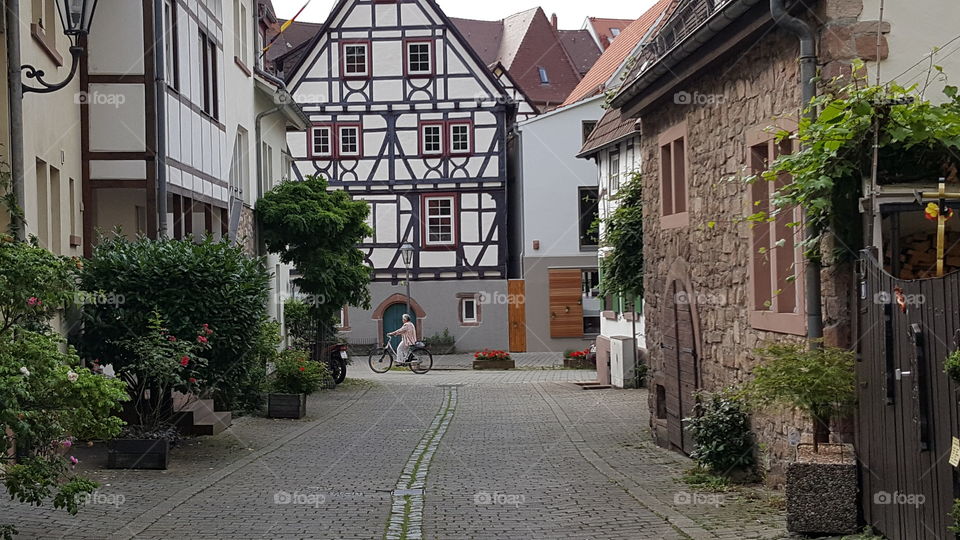 Old lady riding a bike in the old side of a town in germany