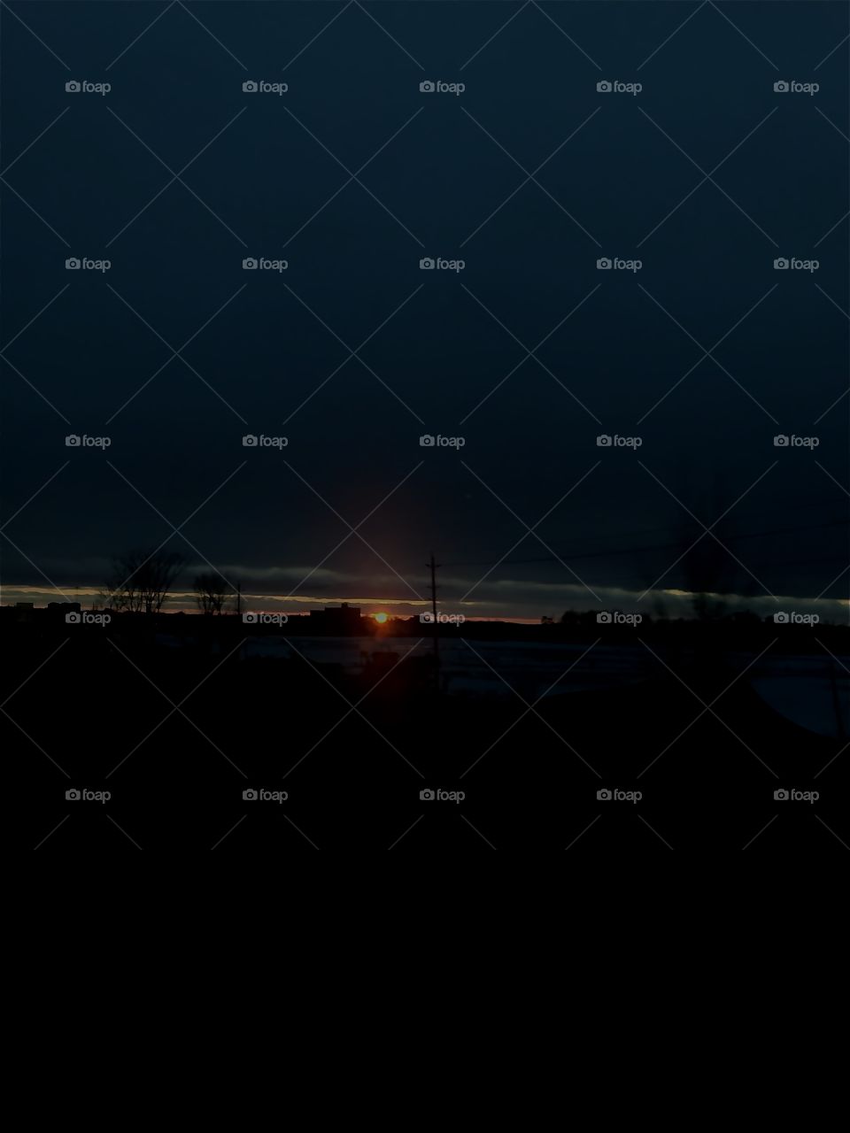 Cloudy, dark, evening sunset over a shadowed landscape.