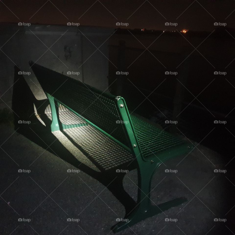 Green bench outside along the old mesh in the netherlands at night