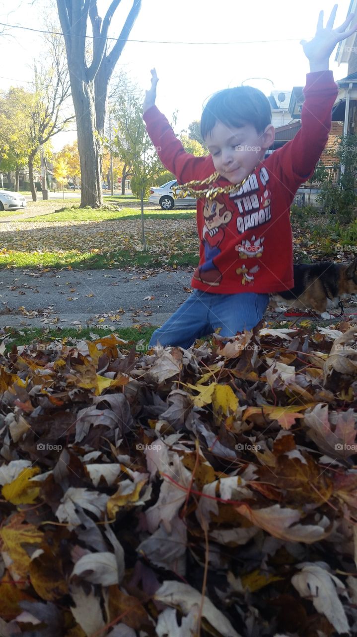 Boy jumping into leaf pile