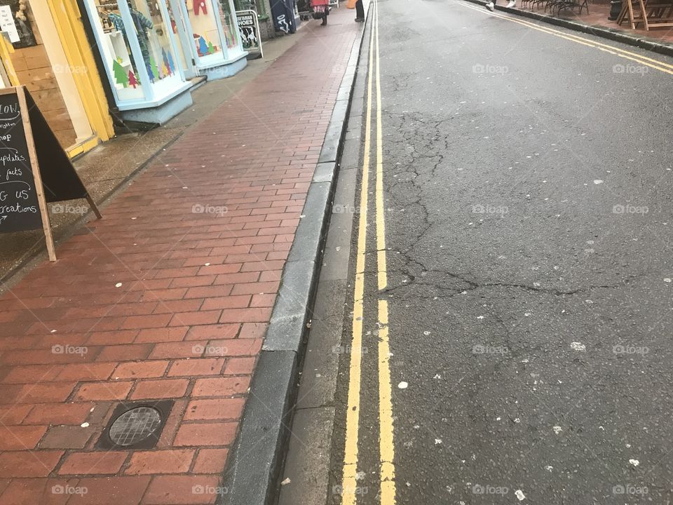 Double yellow lines along a street. Ten bricked path with cracks in the road. 