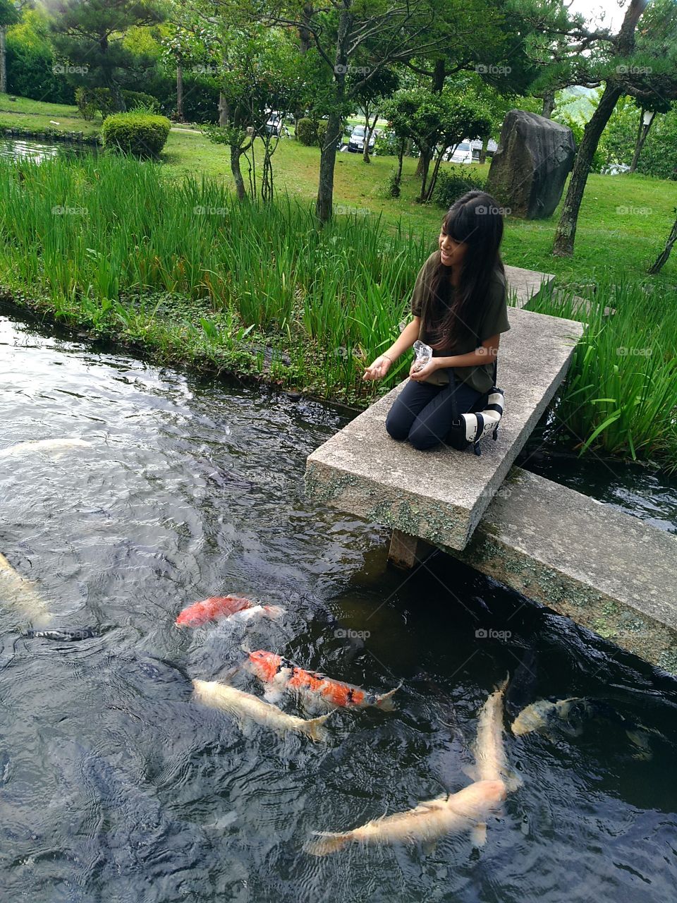 Garotinha alimentando carpas no lago japonês!