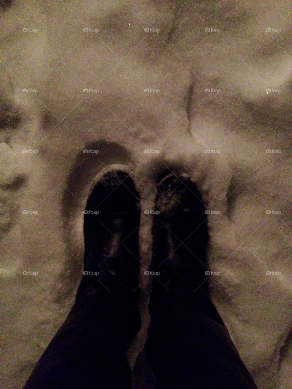 Standing In black shoes on a snow in the night lights