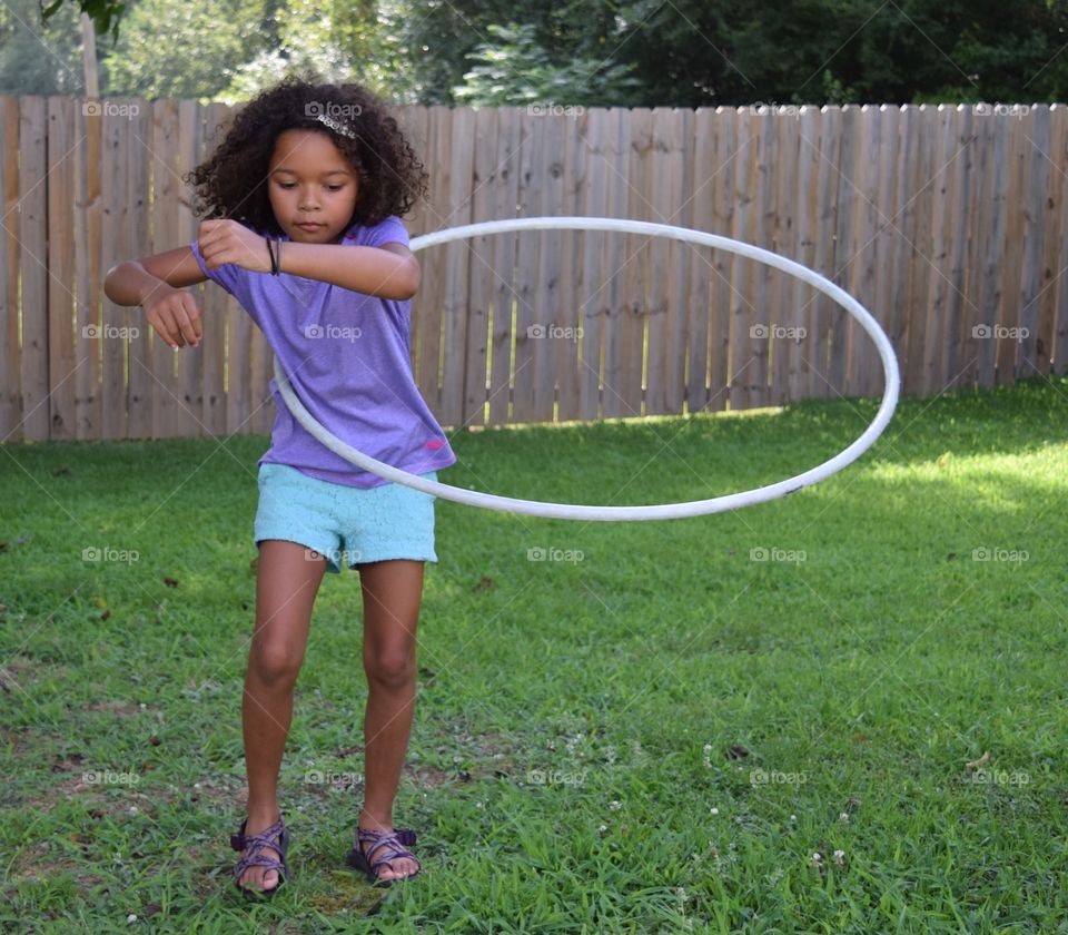 Little girl playing hula hoop in park