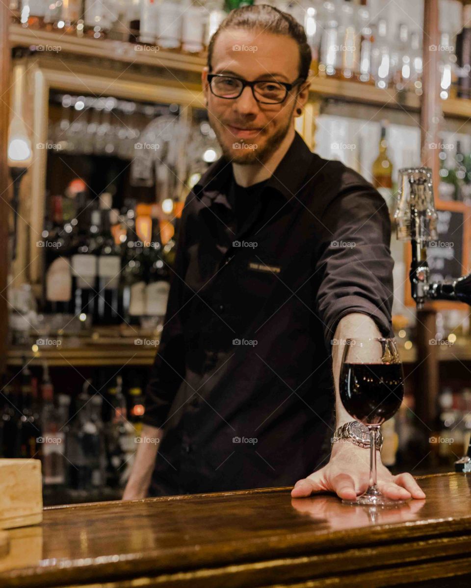Bartender serving a glass of red wine