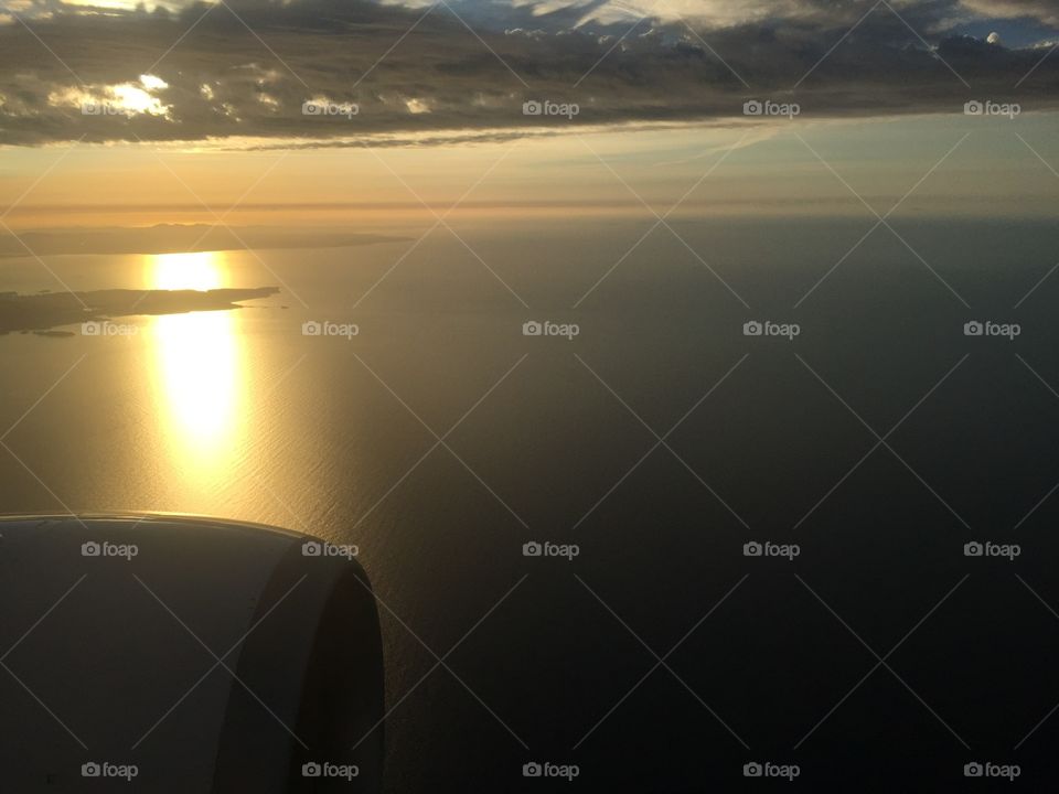 While flying over the sea the sun was mirrored by the sea while hiding behind the clouds. I was lucky by having the window seat to capture this amazing shot. 