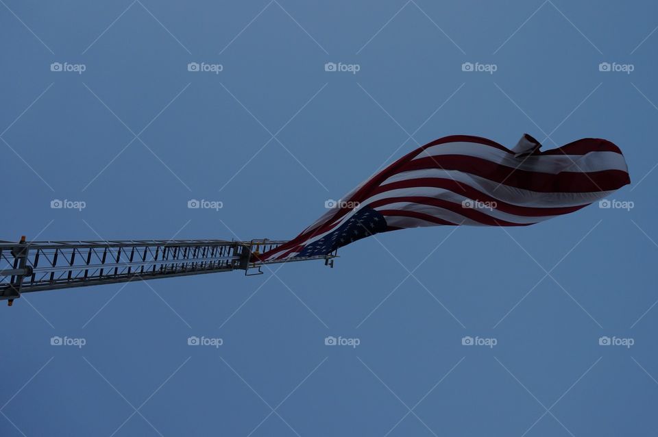 Fire truck ladder flying flag. Looking straight up at the U.S. Flag flying from the fire trucks extended ladder.