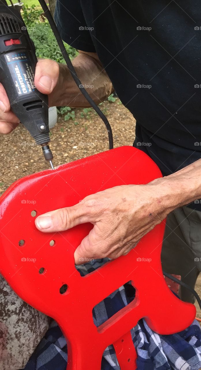 Beautiful red guitar being made with a man's hands. 