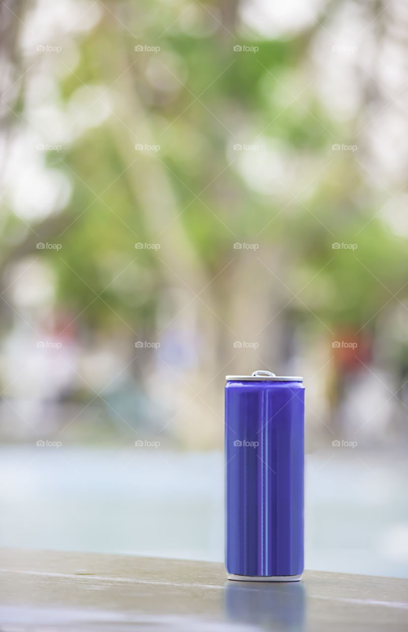 Canned drink blue on the wooden chair Background blurry trees in garden