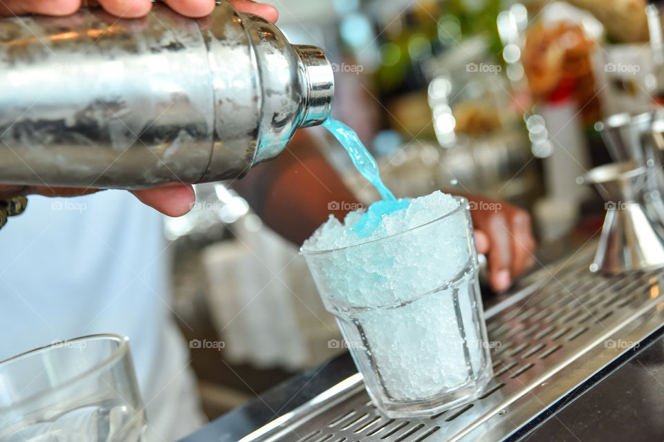 Person pouring juice in glass with ice