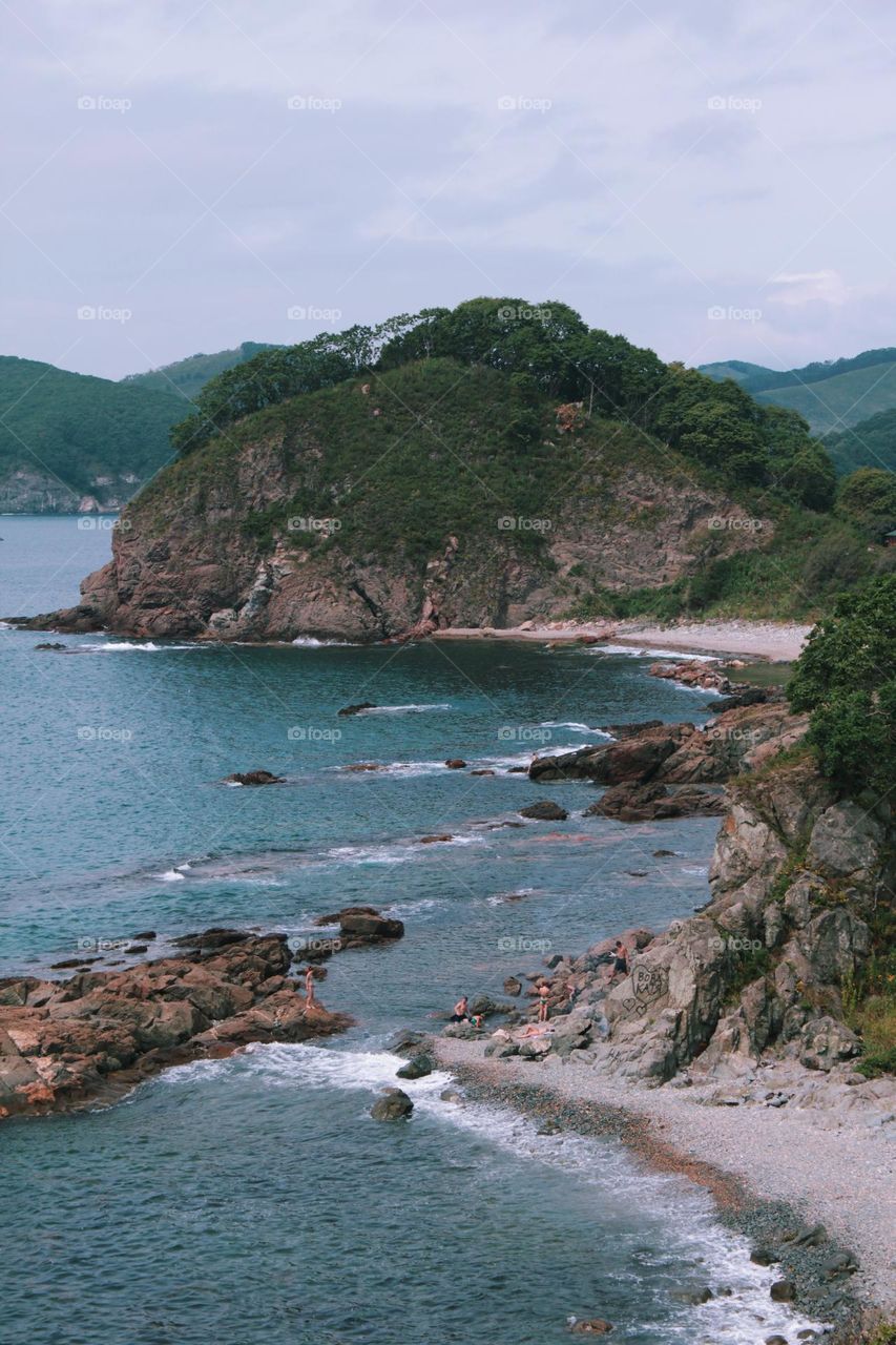 a beautiful sea landscape, blue water and green trees