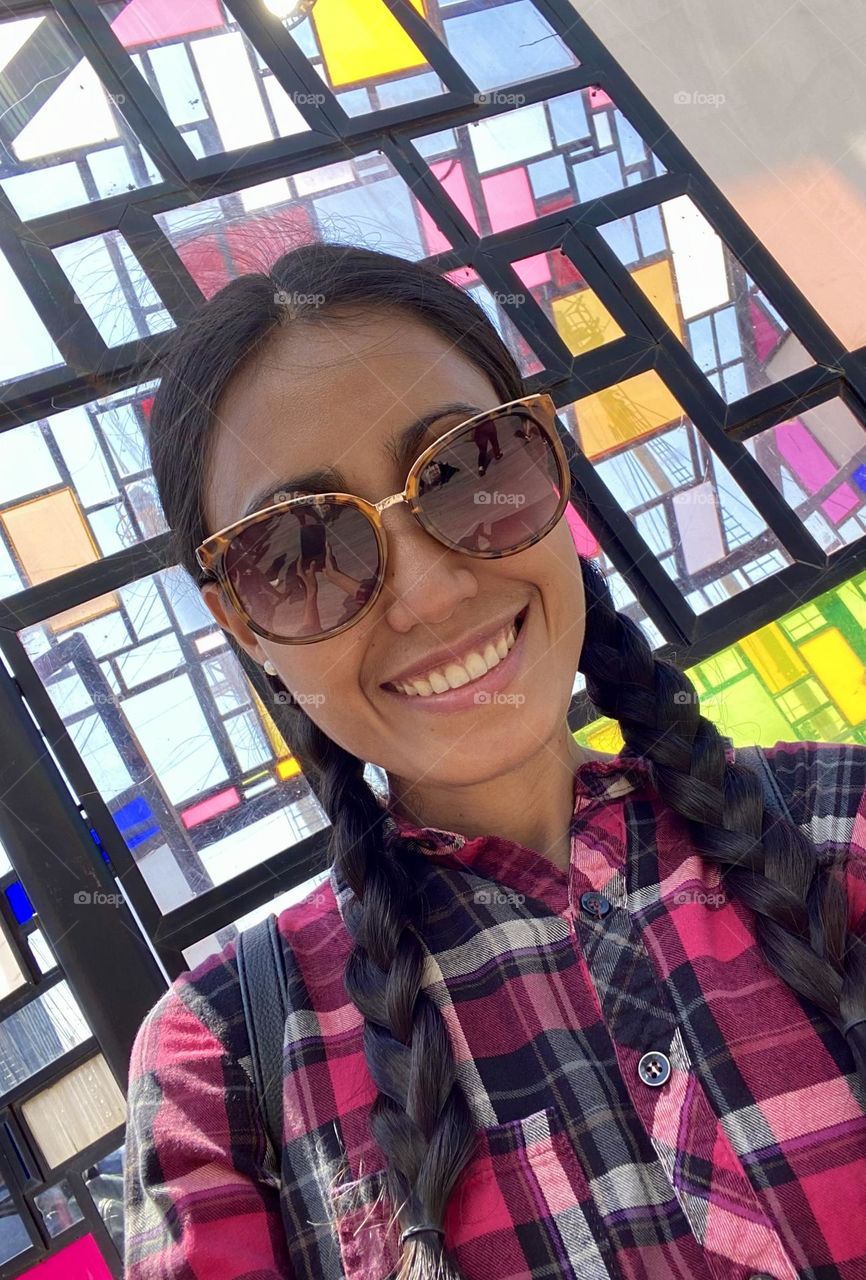 Selfie of a woman wearing checkered clothing that blends into the geometric public art. 