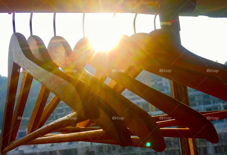 Sunny day = laundry day, morning sunshine with sun rays and bright glare through empty wooden clothes hangers