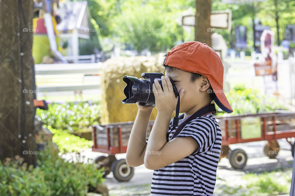 Hand boy holding the camera Taking pictures in park.