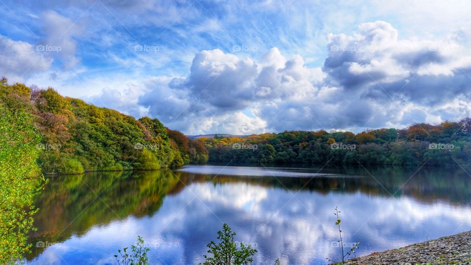 Reflection on the water with the clouds amid autumn trees