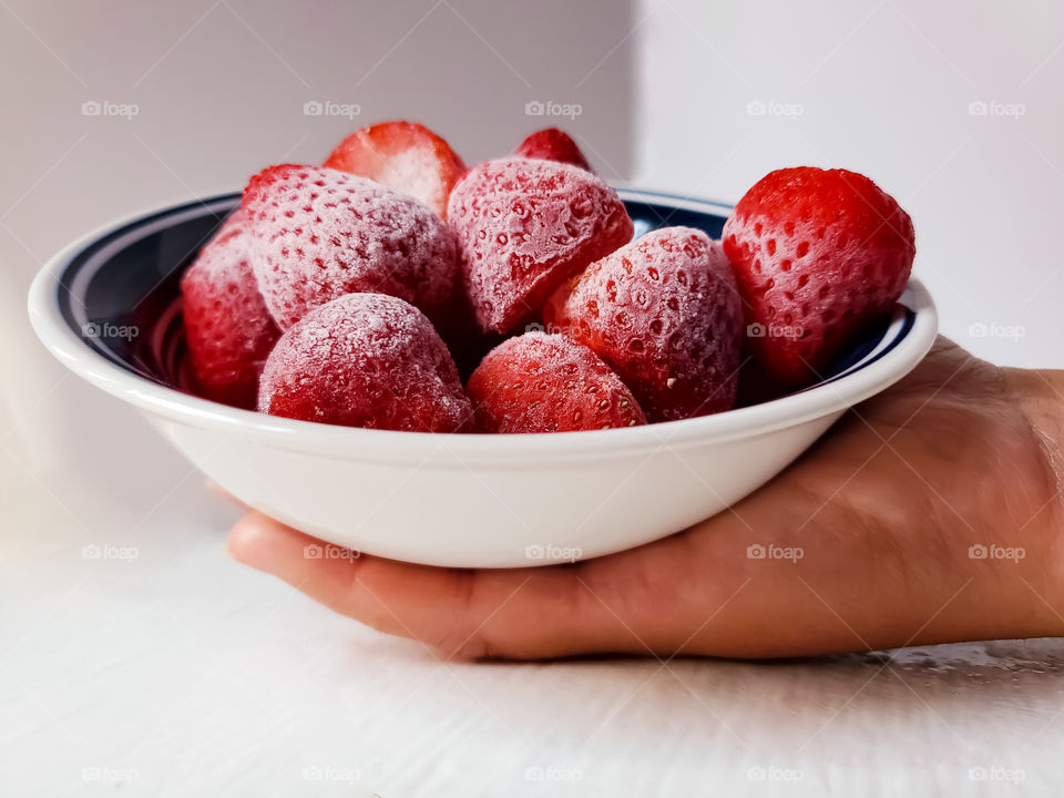Holding a bowl of delicious frozen strawberries!
