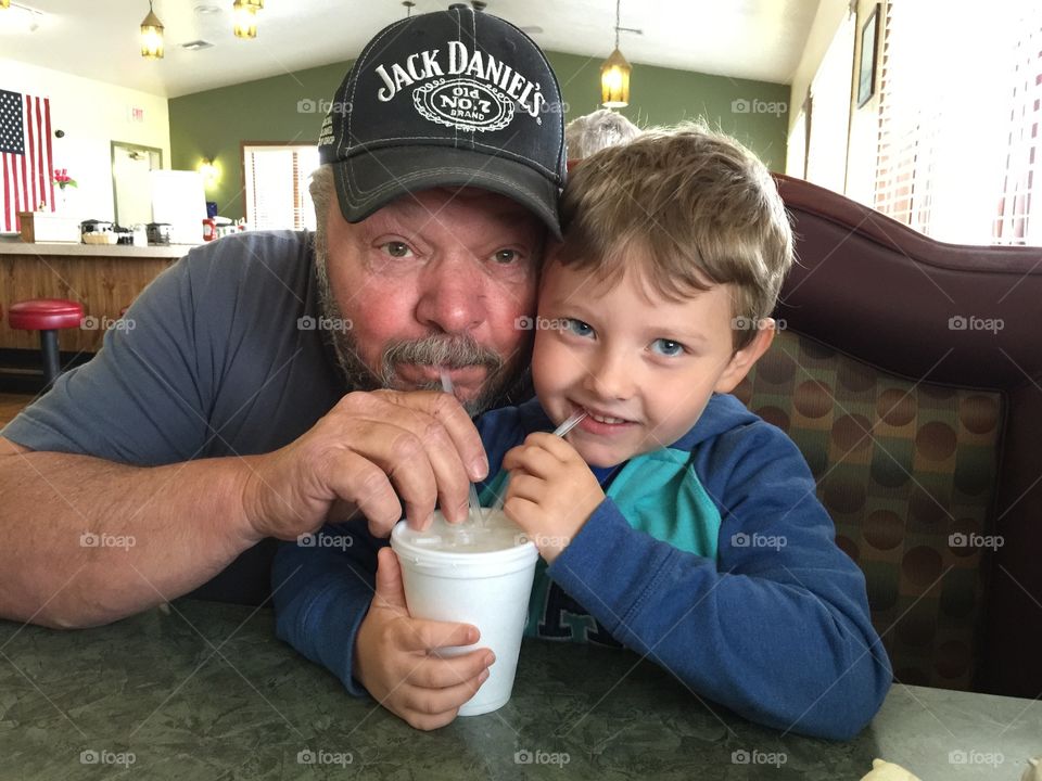 Cute little son and his father drinking milkshake