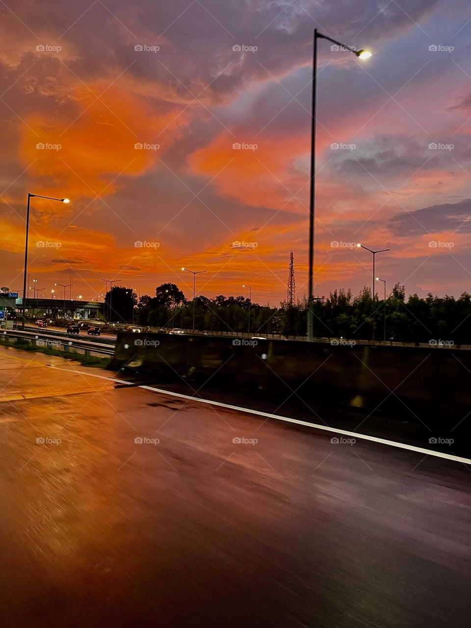 Sunset sky after raining with  beautiful orange water reflections before dark at highway