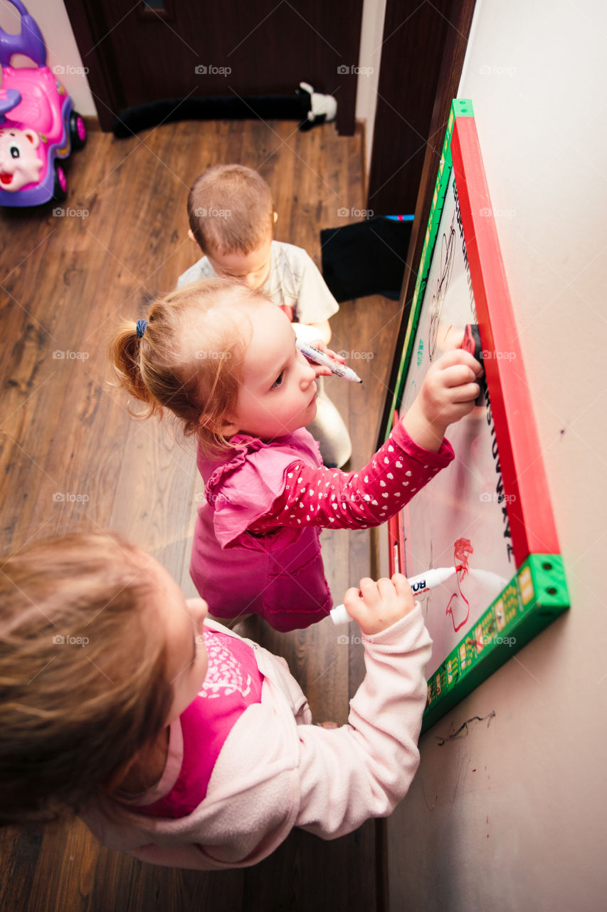 Children drawing a pictures learning a letters playing together using whiteboard and markers