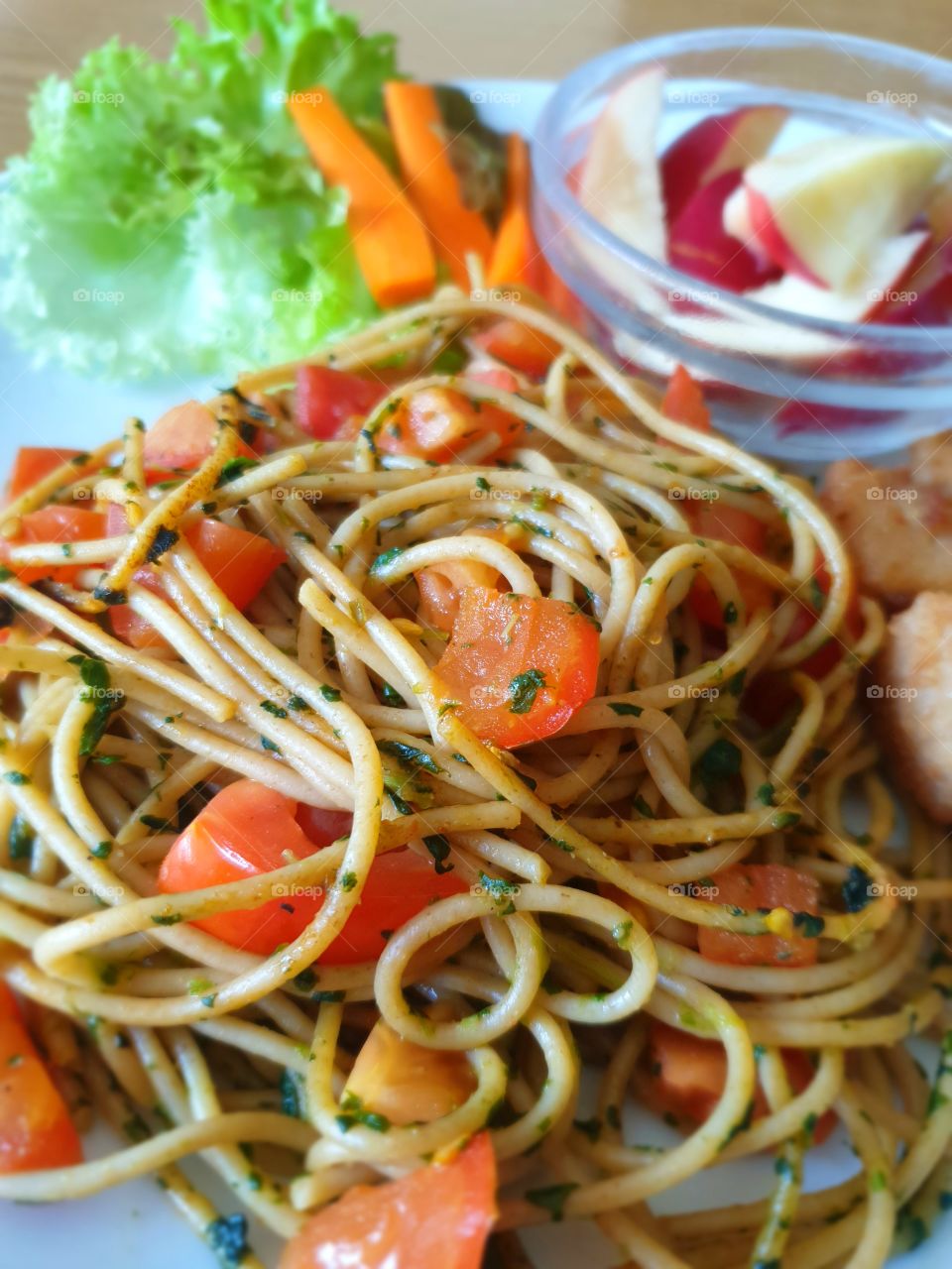 Spaghetti with a tomato and spinach sauce and some veggies.