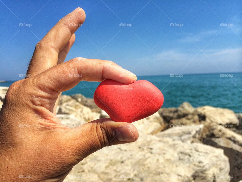 red stone in form of heart with hand