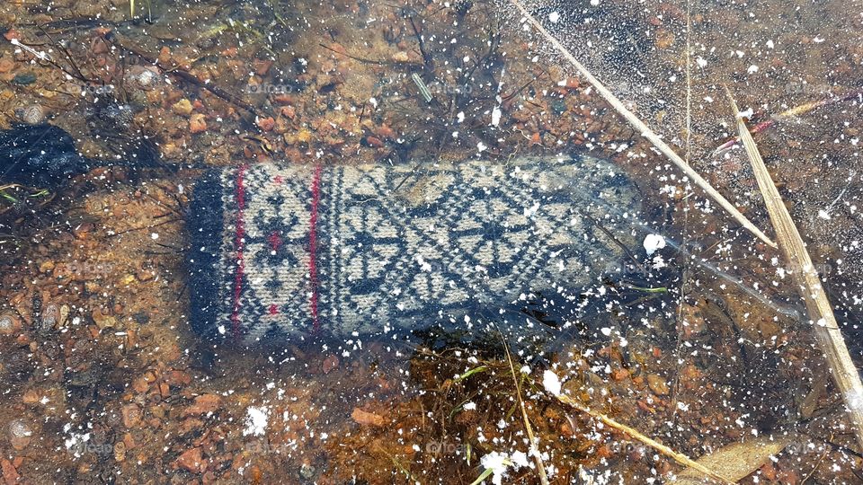 Knitted mitten frozen into the ice of the lake - en stickad vante fastfrusen i isen 