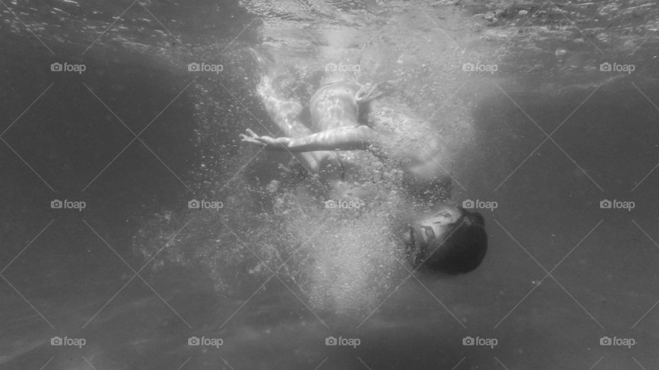 young girl dive underwater, making circles