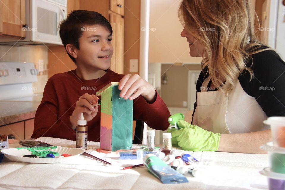 Mom and son painting and decorating bird house indoors 