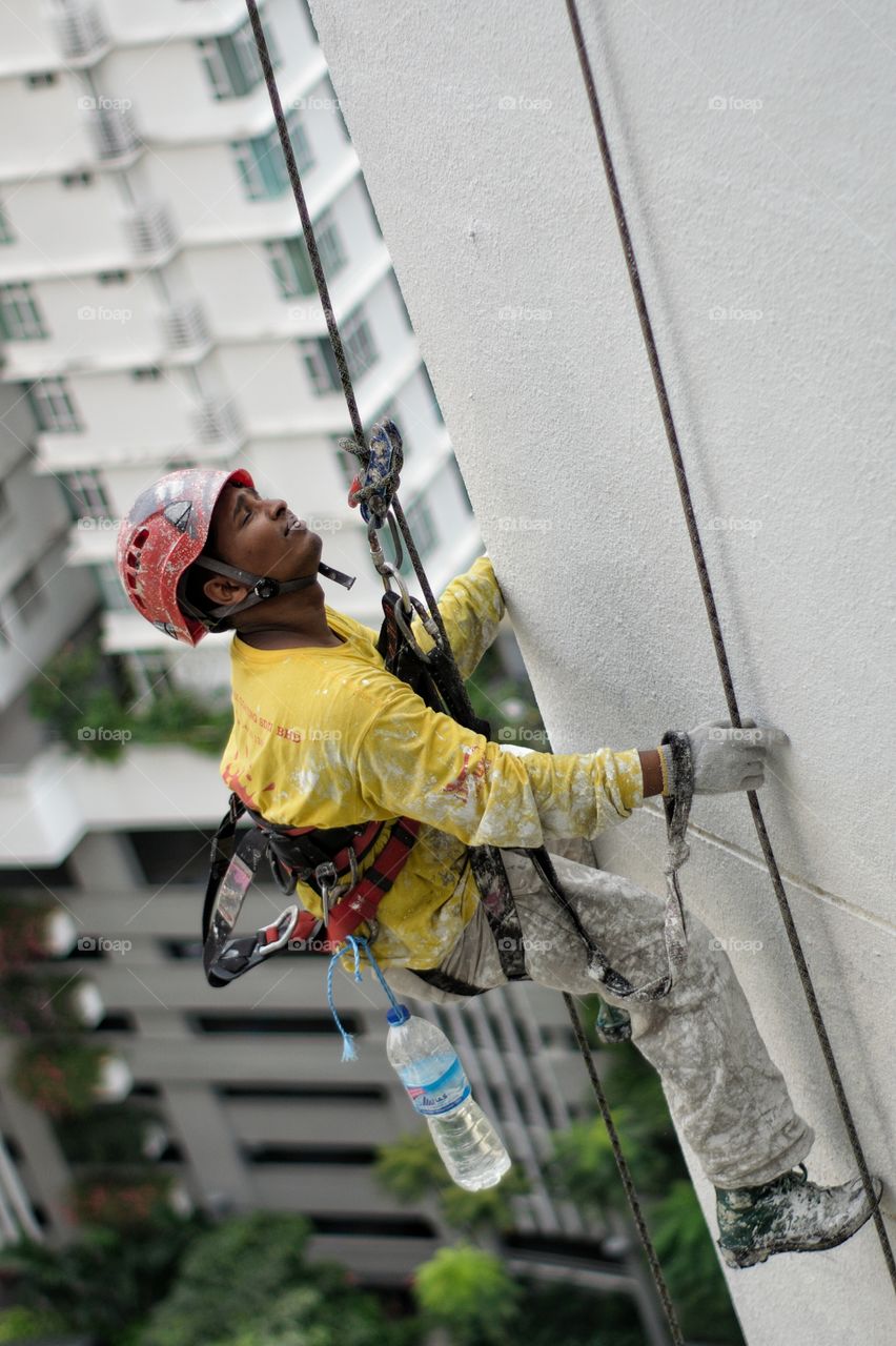 Worker abseiling down side of tower block in Kuala Lumpur Malaysia