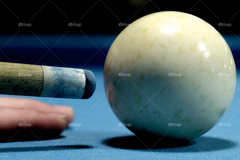 Closeup of a cue stick tip and a cue ball. Pool is a popular hobby shared by many. 