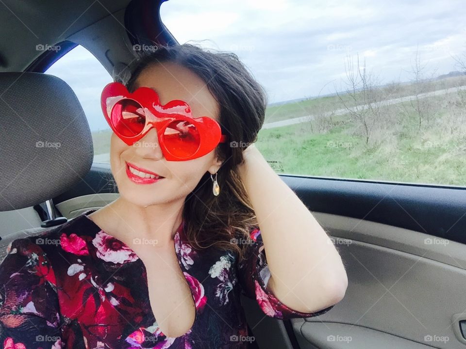 Selfie of woman in the car wearing heart-shaped sunglasses