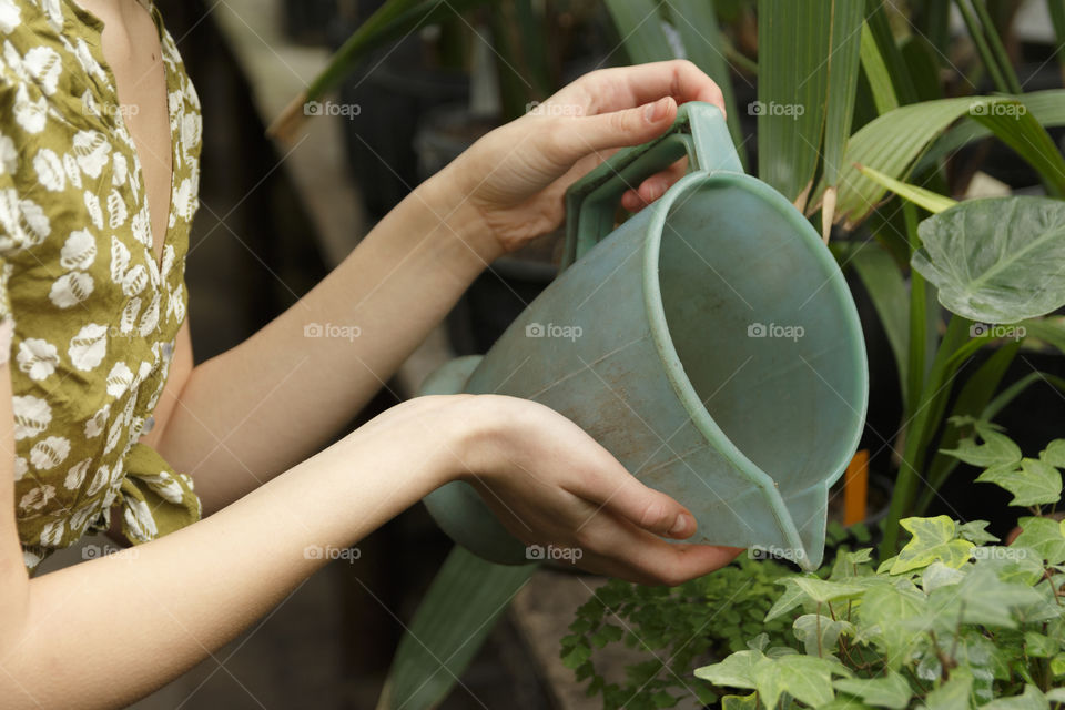 Girl watering plants from a green watering can