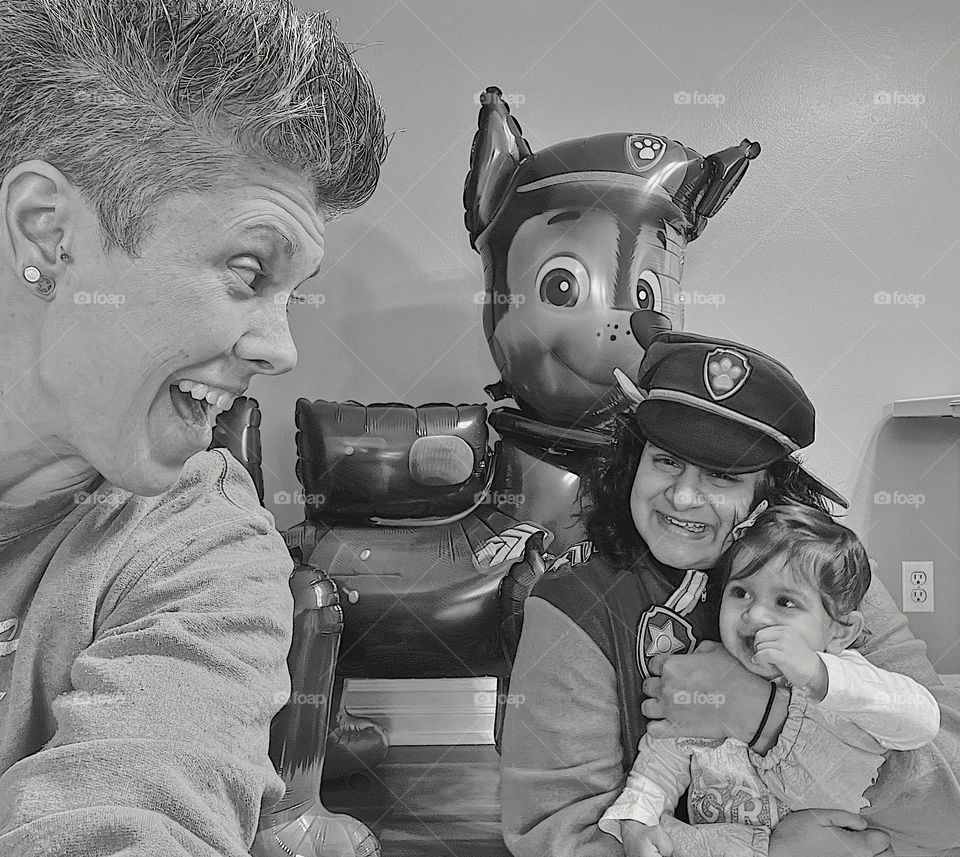 Family with happy facial expressions at birthday party, paw patrol birthday for baby, emotion of happiness being portrayed, family smiling and laughing together, family joking together in happiness, being silly with family, black and white portrait