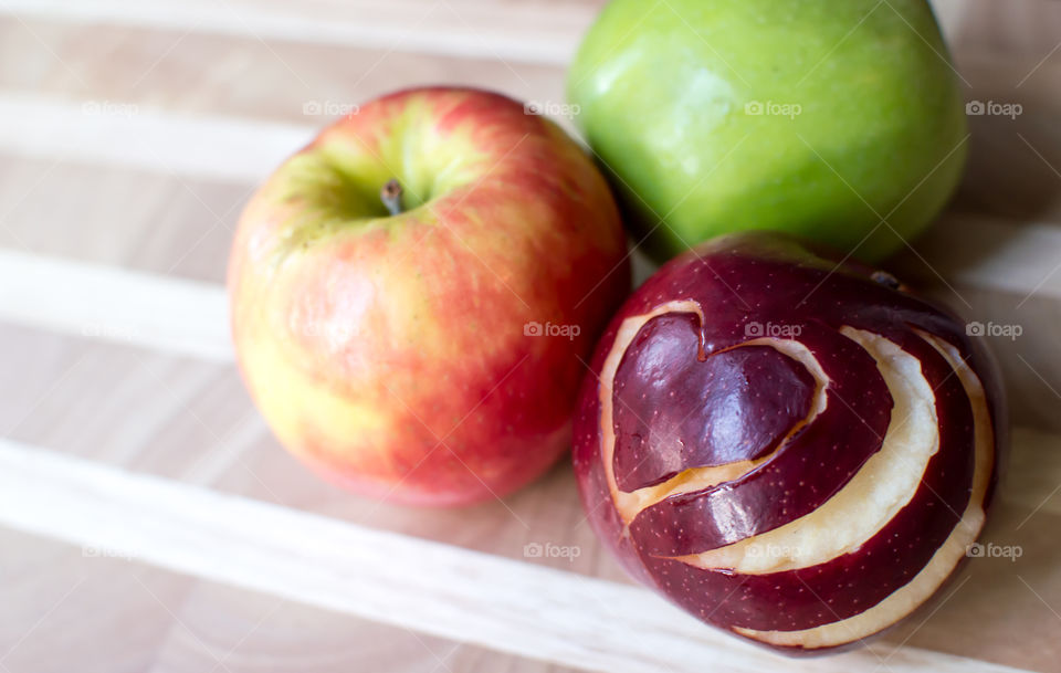 Green apple, red apple and yellow and red apples on wood table with heart shape garnish design on red apple conceptual healthy eating and lifestyle choices photography 