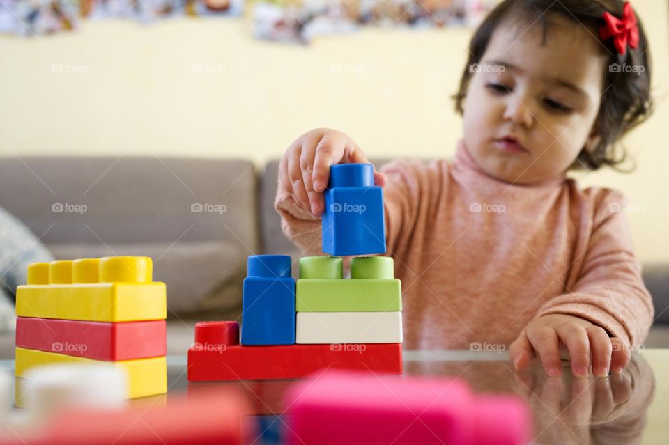 little girl playing rectangular colored constructions