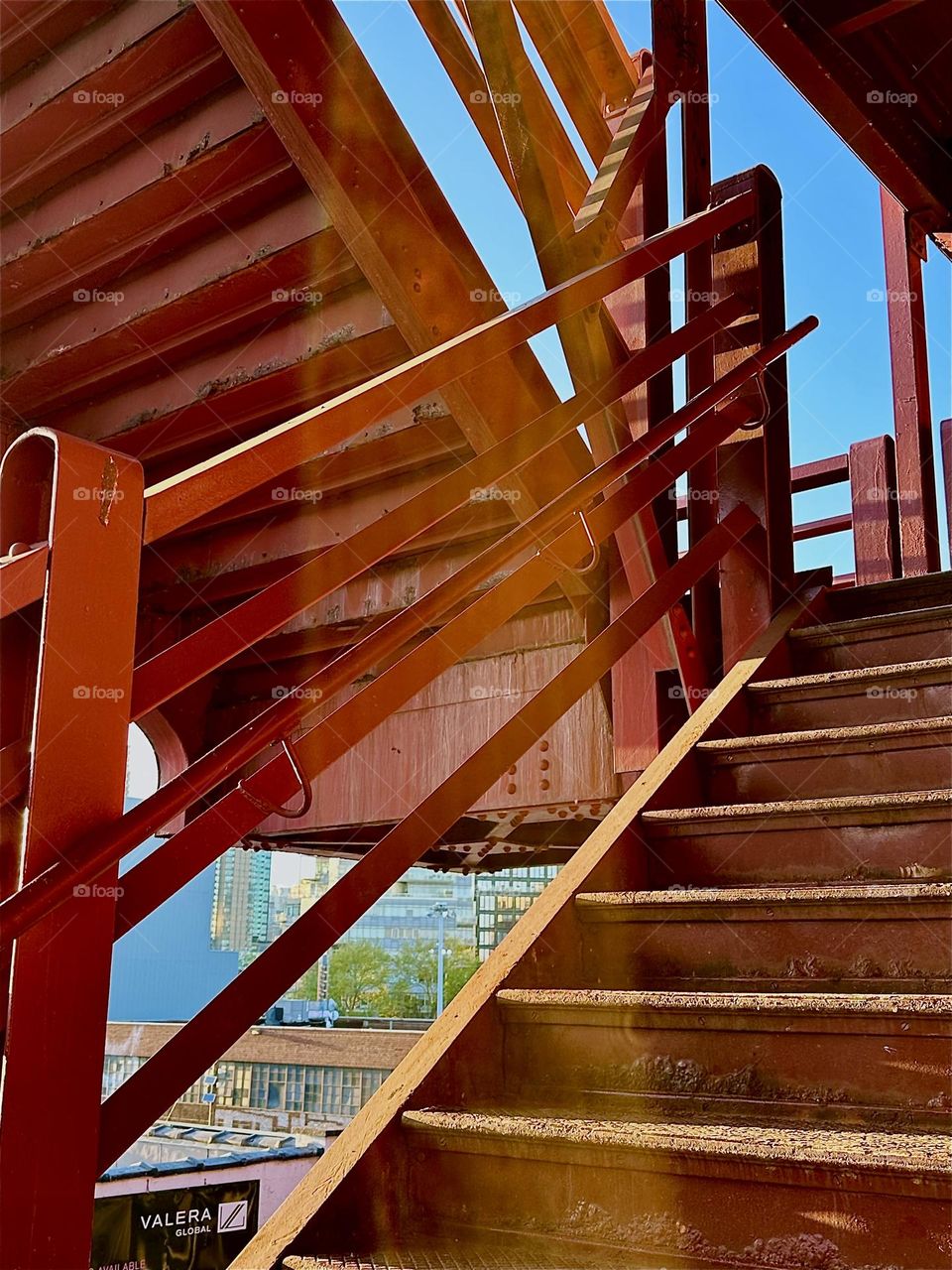 This is the red metal staircase of the „Pulaski Bridge“ at „Newtown Creek“ in LIC, Queens. The warm light of the setting sun visibly passing through illuminates sections of it and gives it a special glow. 2024. Hypnotic Productions