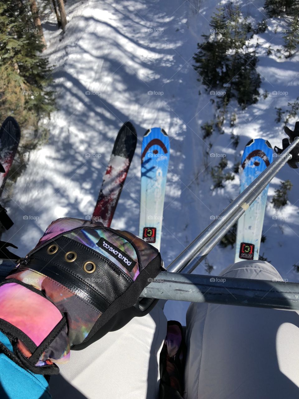 View of poles and skis looking down from the chairlift in winter 