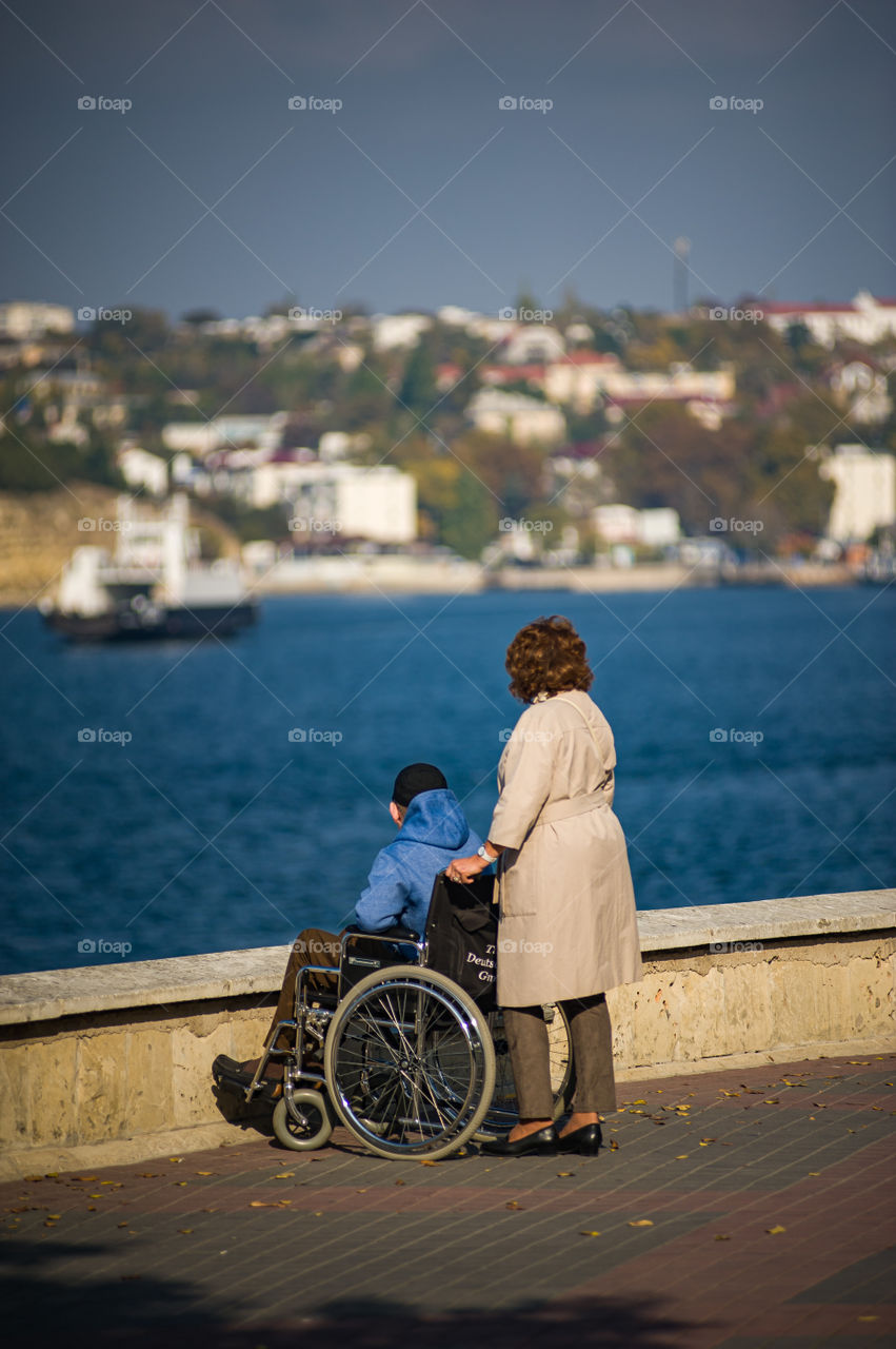 Mom with a disabled son walking in the city center stood near the promenade and enjoy the scenery