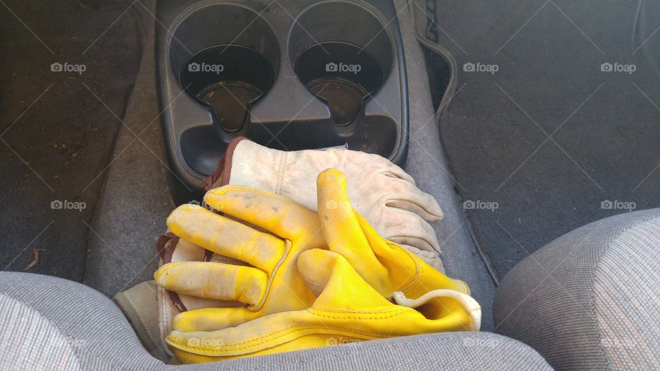 yellow work gloves stacked in pickup truck grey interior black cup holders