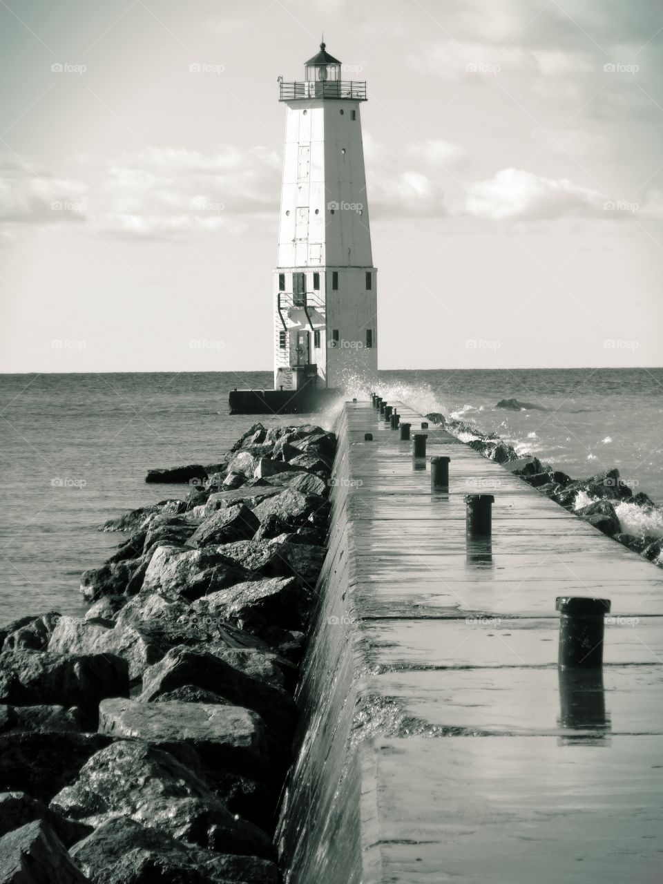 Lighthouse at the end of the pier in sea