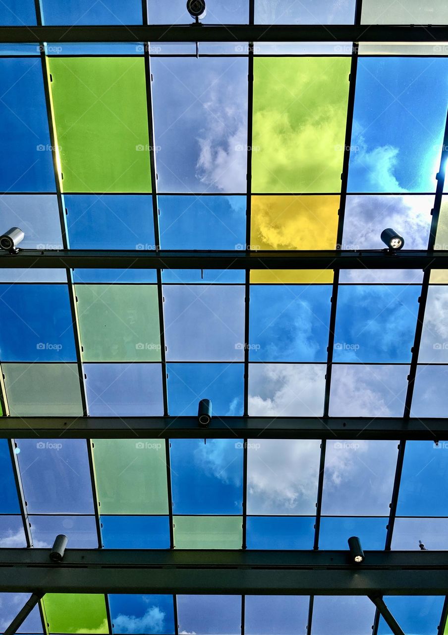 Clouds seen through a ceiling made of multi colored glass panels 