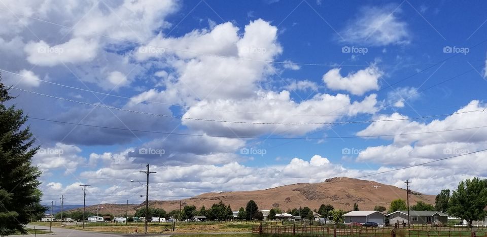 Deep Blue Sky: The rolling clouds cross a crystal blue sky, casting a warm light on the scenic countryside below.