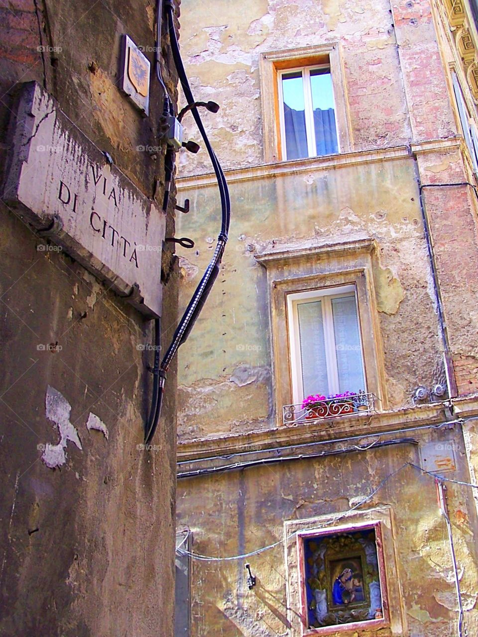 Lovely stone work and windows and sign on buildings in Siena, Spain, via di Citta