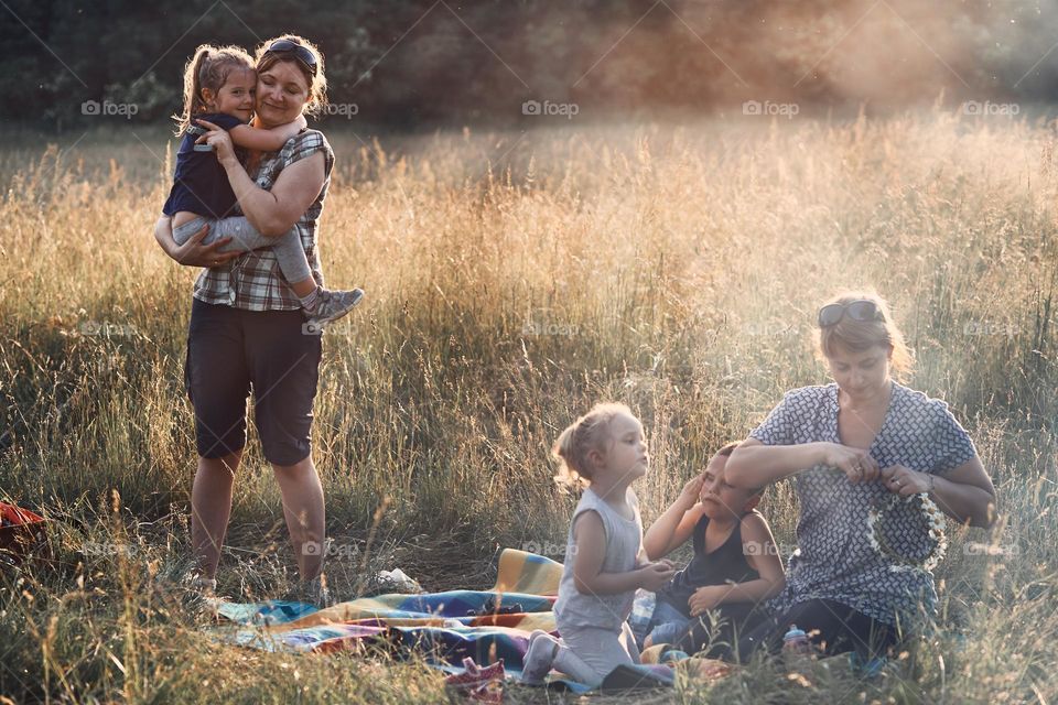 Family spending time together on a meadow, close to nature, parents and children playing together, making coronet of wild flowers. Candid people, real moments, authentic situations