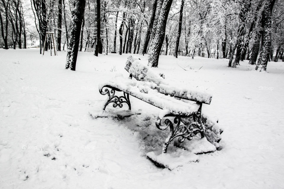 Broken bench. Devastated bench standing in the park. Bench covered with the snow.