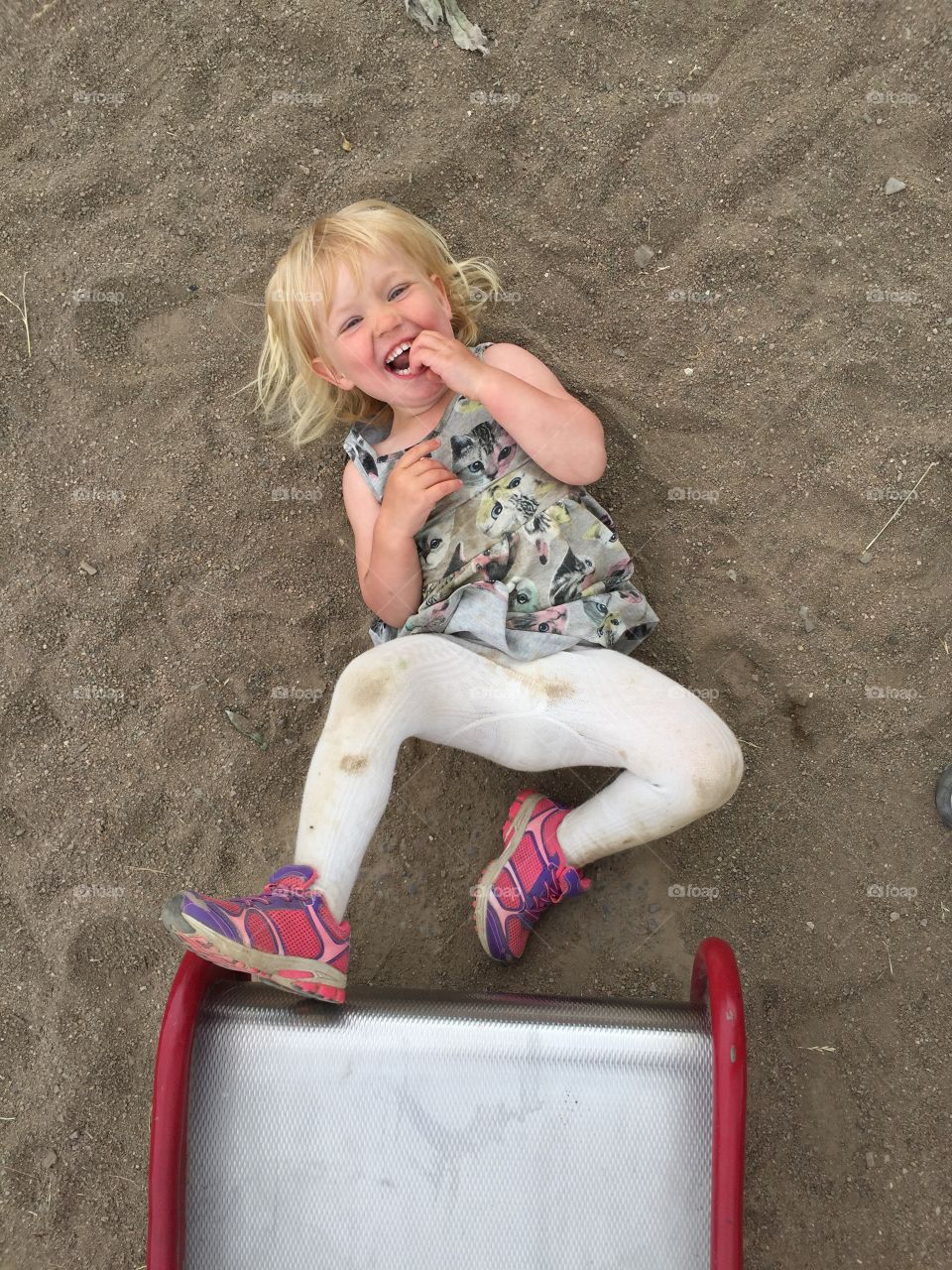 laughing little girl of 2 years old in the sandbox.