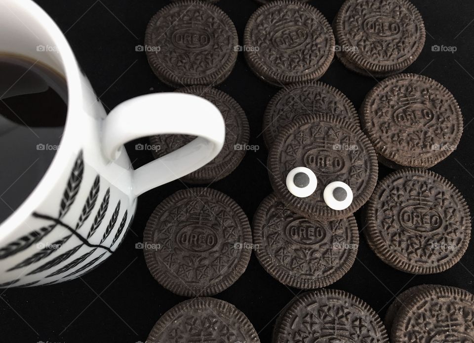 Oreo Cookie Monster .. goggly eyes sat amongst Oreo Original Cookies And a black and white mug.